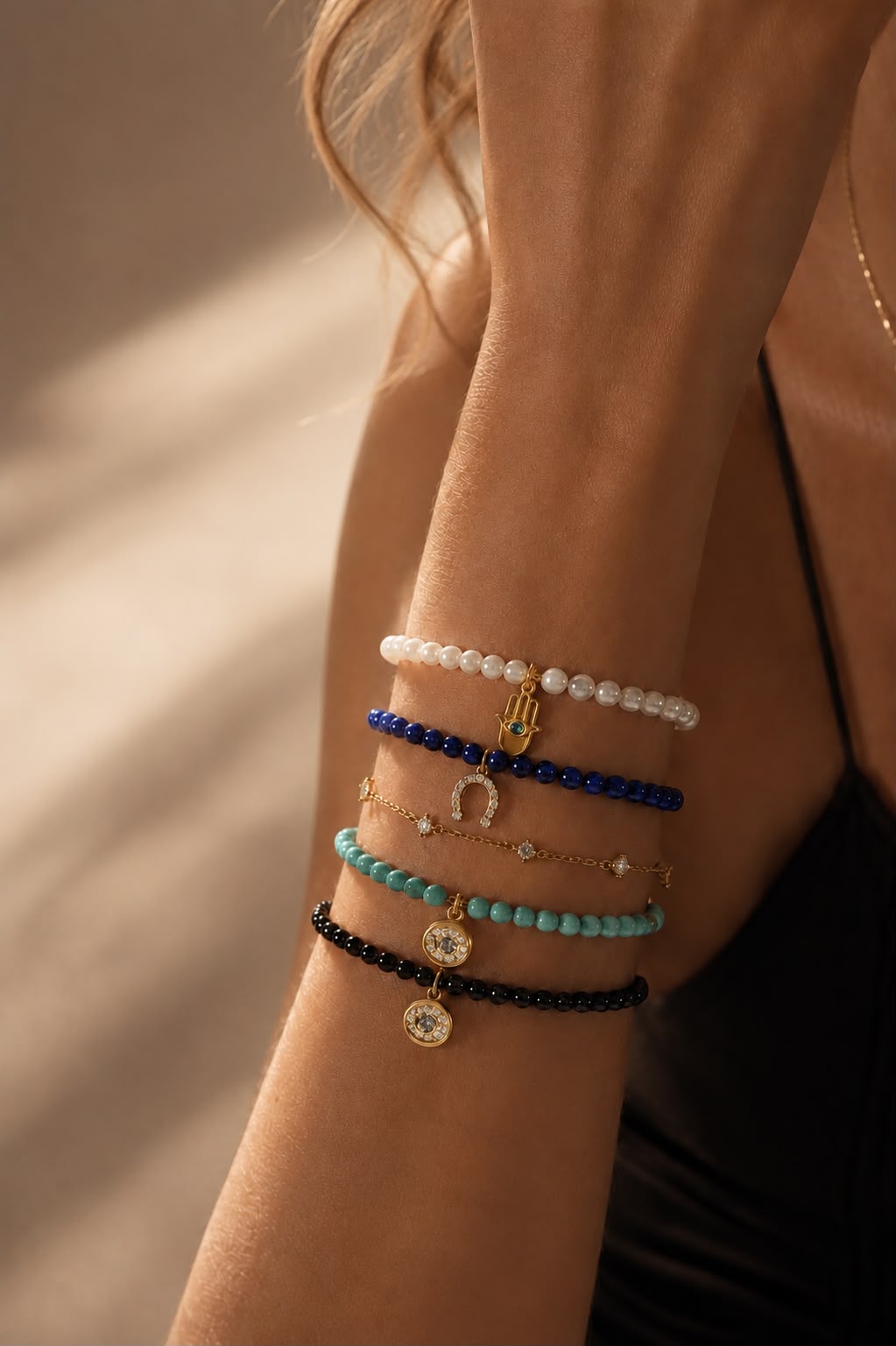 Model wearing Arin spiritual luxury bracelets and bangles in 18k gold plating with Hamsa hand charm - lapis bead cord